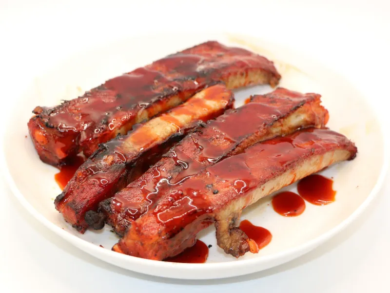 Glazed BBQ pork ribs served on a white plate at Wah Hing Kitchen, a Chinese Restaurant in South Ozone Park